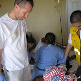 Darren and a Spanish volunteer (yellow vest) helps Dr. John (in bandana) dress wounds in the Minor Procedures Room.