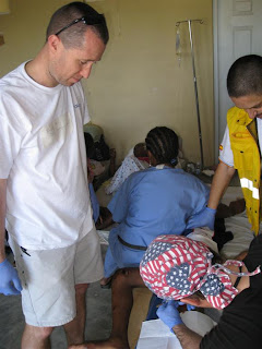 Darren and a Spanish volunteer (yellow vest) helps Dr. John (in bandana) dress wounds in the Minor Procedures Room.