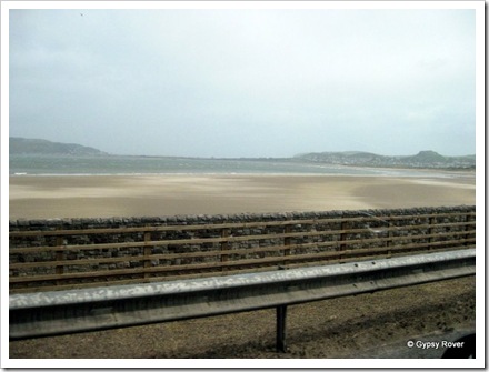 Views from the passenger seat along the sea front at Colwyn Bay. The railway runs between the road and the beach.