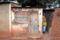 Executive Barber Shop This is the barber shop at the Nami Ntondo market near where I live at St. Gabriel's Hospital. The building is typical for this village, and I get a kick out of the (executive). The woman is wearing a traditional chitengi - a long colorful wrap kind of like a sarong.