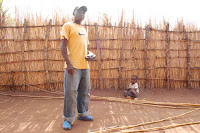 Deus and son prince with home made fishing poles We made this big stack of bamboo fishing poles on a Friday afternoon. You use a machete to cut down a thin bamboo tree that is about fifteen feet long. Then you tie a piece of fishing line to the tip so that the line is just as long as the pole and when you stick the hook in the pole handle, the line stays tight and does not tangle. Just to be sure the line is tied on well, you cut a strip of inner tube rubber that is about as wide as a shoelace, and you wrap it very tight around the tip where the line is tied on. You can see we made a bunch of poles so that each of us could have a couple in the water at once. Deus is about as tall as Carlos, but he looks very big in this picture.