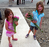 The girls wait excitedly outside with flowers for Mom.