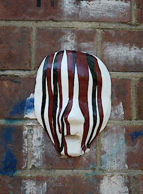 Paint-streaked mask on brick