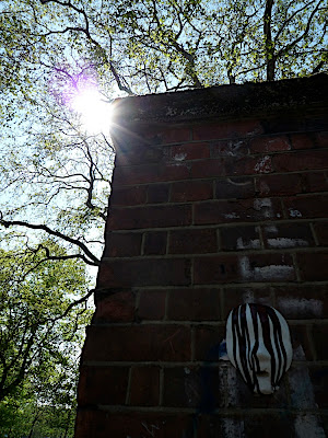 Sun behind brick post with a mask on it