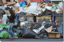 Una donna passa vicino ad una discarica abusiva