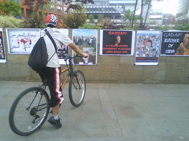 Man on bike looking at poster gallery