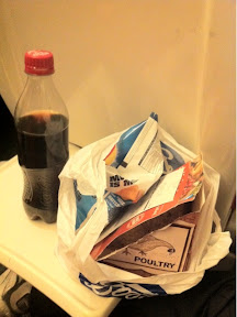 a plastic bag with food in it next to a bottle of soda