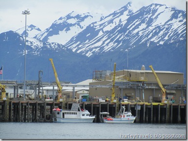 Cranes unloading the catches from fishing boats in Homer Harbor. The top/back of the boat on the left, where there is a row of windows, detaches to make the boat open in good weather.  There were many of these pieces stored across from the harbor.