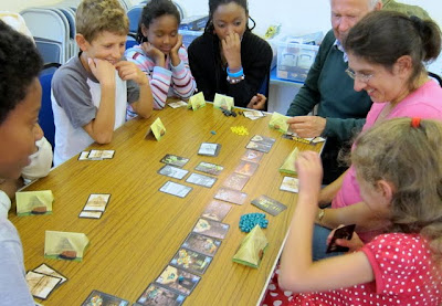 Players of Incan Gold look on in wonder at the amount of gems one player has collected in her exploration of the old temple