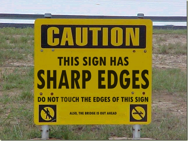 In large letters: Caution! This Sign Has Sharp Edges. Do Not Touch the Edges.  Little letters: Also, the bridge is out ahead.