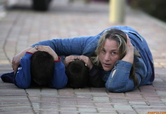RNPS IMAGES OF THE YEAR 2009 - An Israeli woman and her two children take cover during a rocket attack near Kfar Aza, just outside the northern Gaza Strip January 7, 2009. The woman came to meet her husband, an Israeli army officer currently serving on the Gaza border. Rockets exploded as they were waiting for him. Israel postponed on Wednesday a decision on whether to order its armed forces to storm the Gaza Strip's urban centres, an Israeli official said, citing Egyptian- and French-led efforts to secure a truce with Hamas. REUTERS/Baz Ratner (ISRAEL POLITICS CONFLICT)