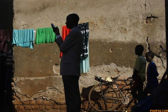 RNPS IMAGES OF THE YEAR 2009 - A town official accompanying visiting journalists sends a text message on his phone in the slum of Kachuf in the Masaka district of southern Uganda March 24, 2009.  The word 'Kachuf' in Luganda means 'dirt'.  MALTA OUT. NO COMMERCIAL OR EDITORIAL SALES IN MALTA  REUTERS/Darrin Zammit Lupi (UGANDA)