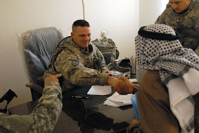 Sgt. Brian Wilson, from Fort Lewis, Wash., attached to “B” Co., 2nd Bn., 69th Armor Regt., congratulates a farmer in Khidr after he signs an economic project contract that will provide him with 30 turkeys and feed to support them, Jan. 12. The contracts, aimed at helping the needy in northern Babil Province, will give struggling families a way to support their families without having to turn to terrorist cells for support.