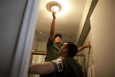 Venezuelan soldiers replace incandescent light bulbs with energy saving bulbs in a house in Caracas March 8, 2010. REUTERS / Carlos Garcia Rawlins