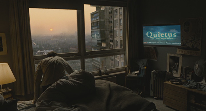 Screenshot from “Children of Men” showing Clive Owen and a television ad for Quietus, a suicide drug, with the slogan: “You Decide When”. (dir. Alfonso Cuarón, 2006). Graphic: Universal Studios