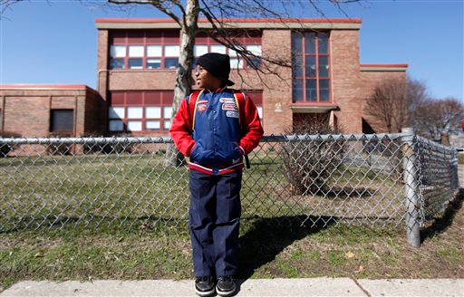 Tylan Franklin, 8, stands outside Bunche Elementary in Detroit, Wednesday, March 17, 2010. Doors are expected to shut on more than a quarter of Detroit's 172 public schools in June as the district fights through steadily declining enrollment and a budget deficit of more than $219 million, an emergency financial manager said Wednesday. Bunche is scheduled to close in June of 2010. (AP Photo / Paul Sancya)