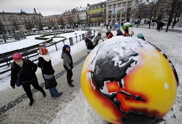 People stop to look at a snow-covered 'Cool Globe' part of an exhibition about combating global warming and climate change in the Kongens Nytorv area in the center of Copenhagen on December 19, 2009 at the end of the COP15 UN Climate Change Conference. Photograph by: Getty Images
