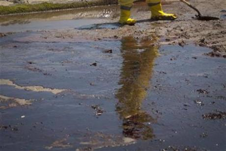 A clean-up worker is reflected in a pool of beached oil from the Deepwater Horizon Oil Spill in Port Fourchon, Louisiana May 24, 2010. Credit: Reuters / Lee Celano