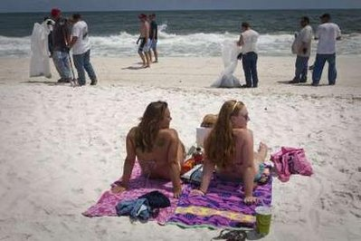 Two women look on as contract workers clean oil globs from the Deepwater Horizon oil spill blanket a beach in Pensacola Beach, Florida June 4, 2010. REUTERS / Lee Celano