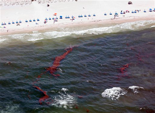 People walk along the water in Gulf Shores, Alabama, Saturday, 5 June 2010 as streams of oil approach the beach. Oil from the Deepwater Horizon oil spill has started washing ashore on the Alabama and Florida coast beaches. AP Photo / Dave Martin