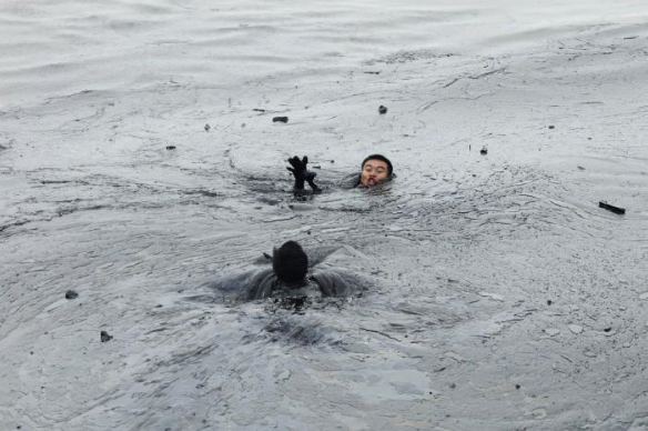 A worker attempts to rescue his co-worker from drowning in an oil slick while attempting to fix an underwater pump during oil spill clean-up operations at Dalian's Port in China's Liaoning province July 20, 2010. REUTERS / Jiang He / Greenpeace
