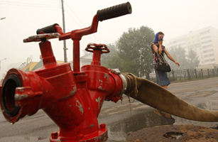 A woman covers her nose from smog as she walks next to a fire hydrant in the town of Vyksa, some 93 miles (150 km) southwest of the Volga city of Nizhny Novgorod, on July 31, 2010. Mikhail Voskresensky / Reuters