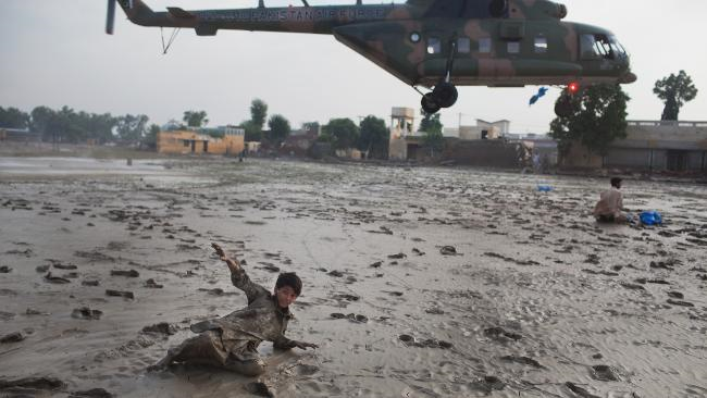 A boy is flung back by the force of a Pakistan Air Force helicopter dropping water supplies to residents in Nowshera, 3 August 2010. Getty Images