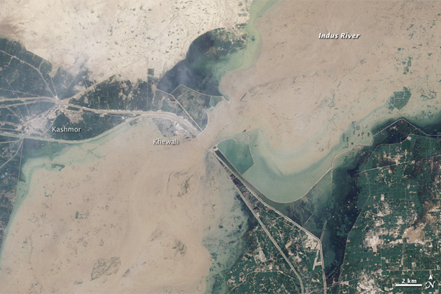 This image was acquired by the Landsat 5 satellite on August 12, 2010, showing flooding near Kashmor, Pakistan, just before the second wave of the flood hit. As if constrained by a belt, the river is cinched near Khewali. The constraint is the Guddu Barrage, a barrier designed to channel irrigation water to farmland in the northern Sindh district. Canals extend away from the barrage on both sides of the river. NASA image by Robert Simmon, based on Landsat 5 data from USGS