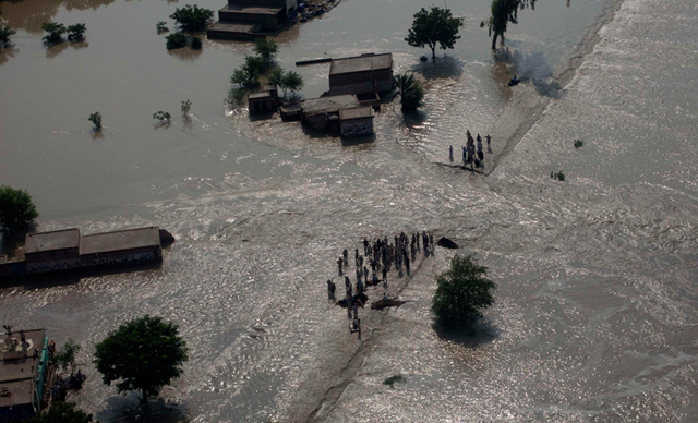 Residents stand near the path of flowing flood waters the Muzaffargarh district of Pakistan's Punjab province on August 9, 2010. REUTERS / Adrees Latif