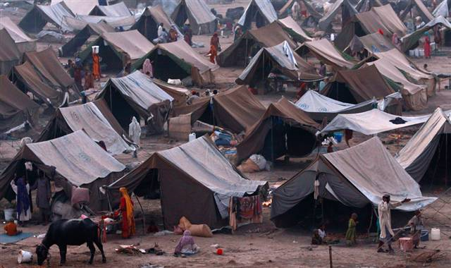 People stand outside their tents at a camp for those displaced by floods in Sukkur, southern Pakistan, 4 October 2010. Aaron Favila / AP
