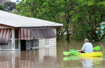 A resident evacuates his flooded home by kayak in Bundaberg on December 29, 2010 after entire towns were inundated by the worst deluges in decades. Thousands of people prepared to flee floods in Australia's north-east Thursday as rising waters swamped towns, roads and railways in an 'unprecedented' multi-billion-dollar disaster. AFP / Pool / Jono Searle