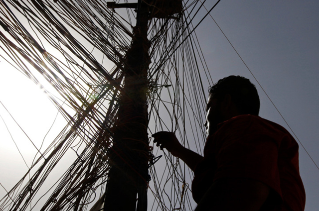 In this photo Abbas Ahmed navigates a network of generator wires during a power outage in Baghdad, Iraq on June 25, 2010. Private power providers in Baghdad are selling electricity at almost four times the maximum legal price, exploiting shortages and stifling summer heat while crime bosses pilfer dwindling public supplies. AP Photo / Hadi Mizban