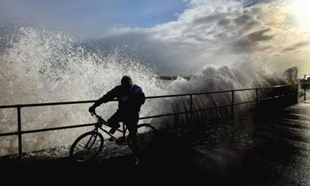 A cyclist is caught out by a huge wave in Great Yarmouth in 2007. East Anglia is one of five areas particularly at risk from rising sea levels caused by climate change. Photograph: Jamie McDonald / Getty Images / guardian.co.uk