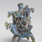 During Roman and early Islamic times, a popular type of vessel was a single, double, or quadruple glass cosmetic tube intricately decorated with trailed glass threads. In the Islamic examples, these tubes are carried on the backs of domestic animals, and the trailed threads are meant to imitate wicker baskets or cages protecting the bottle.