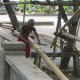 A man carves bamboo to be used as material for building a boat