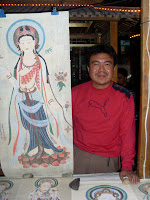 Man proudly standing by his paintings
