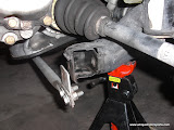 Unhook lower brace if you have one and front control arm bolt