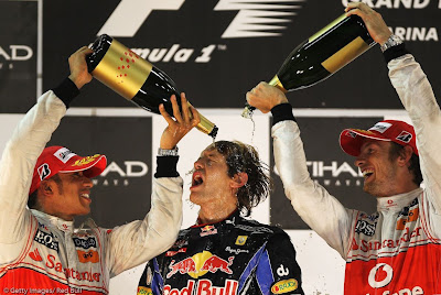 Льюис Хэмилтон и Дженсон Баттон поливают Себастьяна Феттеля победным шампанским на Гран-при Абу-Даби 2010