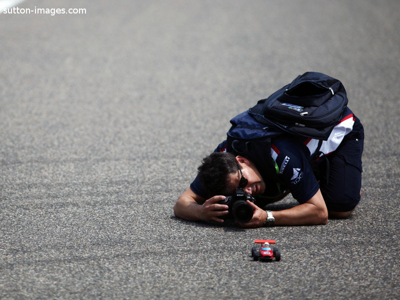 фотограф на Гран-при Китая 2011 снимает игрушечную машинку на настоящем гоночном треке