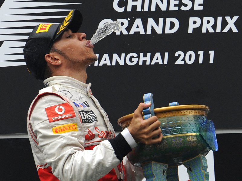 Льюис Хэмилтон пускает струю шампанского в Шанхайски трофей на подиуме после победы на Гран-при Китая 2011