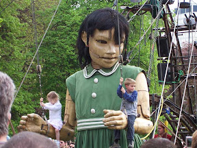 The girl kneeling with two kids swinging on her arms
