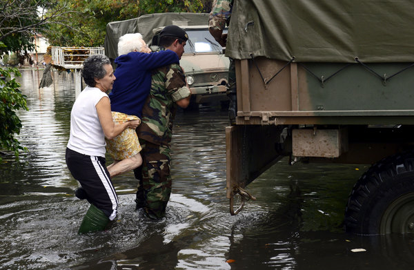 A soldier evacuates an elderly woman in a flooded street in La Plata, a provincial capital 30 miles from Buenos Aires, 3 April 2013. Photo: Daniel Garcia / Agence France-Presse / Getty Images