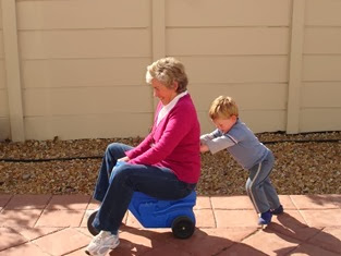 Child_pushing_grandmother_on_plastic_tricycle