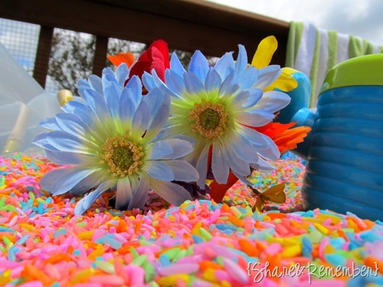 Silk flowers and watering can for gardening sensory bin with Rainbow Rice & Garden Sensory Play