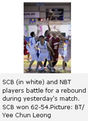SCB (in white) and NBT players battle for a rebound during yesterday's match. SCB won 62-54.Picture: BT/ Yee Chun Leong 