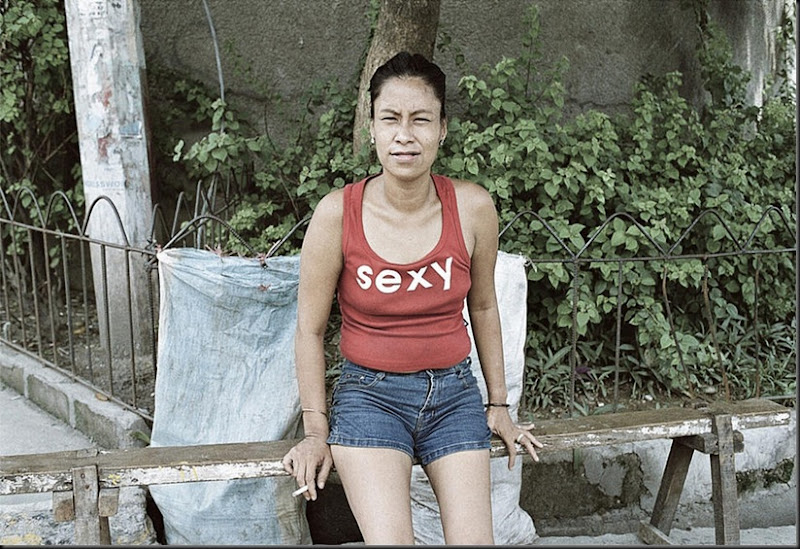 A resident of Malabon city in Manila smokes a cigarette on a wooden bench outside the street after eating lunch.