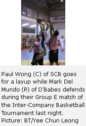 Paul Wong (C) of SCB goes for a layup while Mark Del Mundo (R) of D'Babes defends during their Group E match of the Inter-Company Basketball Tournament last night. Picture: BT/Yee Chun Leong 