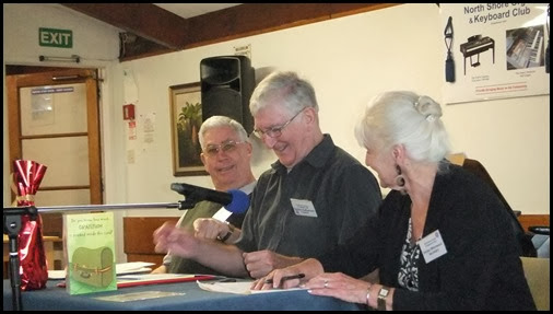 Holding the AGM. The microphone kept drooping more and more which seemed to cause huge amusement. Left to Right: Jim Nicholson (outgoing Treasurer); Gordon Sutherland (President); and, Delyse Whorwood (Secretary). Photo courtesy of Dennis Lyons.