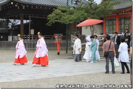 八坂神社-紙園祭，新人的前面有兩位前導，還有人為新娘特別撐傘，後面還跟著家屬及賓客，其實旁邊還有穿西裝的人員維持秩序，排除擋道的遊客。 