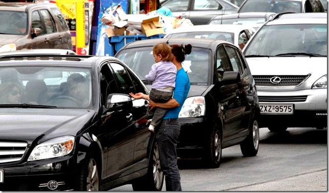 A woman carrying small child begs at a traffic light in the upscale suburb of Glyfada, south of Athens on Monday, Nov. 22, 2010. Greek charity groups have warned of a surge in homelessness and poverty in the Greek capital, caused by the recession and drastic austerity measures taken by the eurozone member to avoid bankruptcy and receive international bailout loans. (AP Photo/Dimitri Messinis)